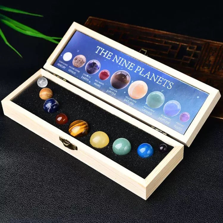 Set of model planets in a wooden box with 'The Nine Planets' label on a dark background