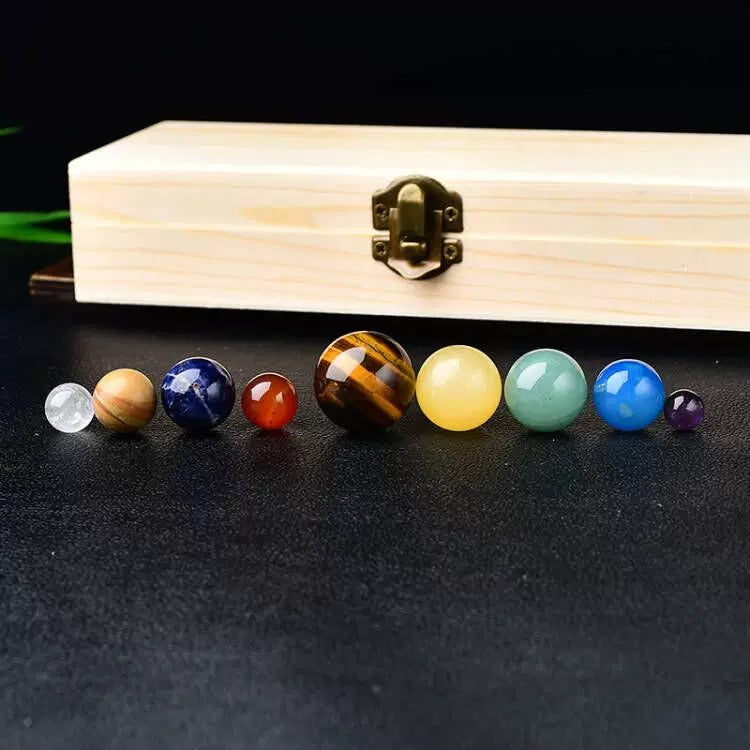 Set of colorful gemstones in front of a wooden box on a dark surface